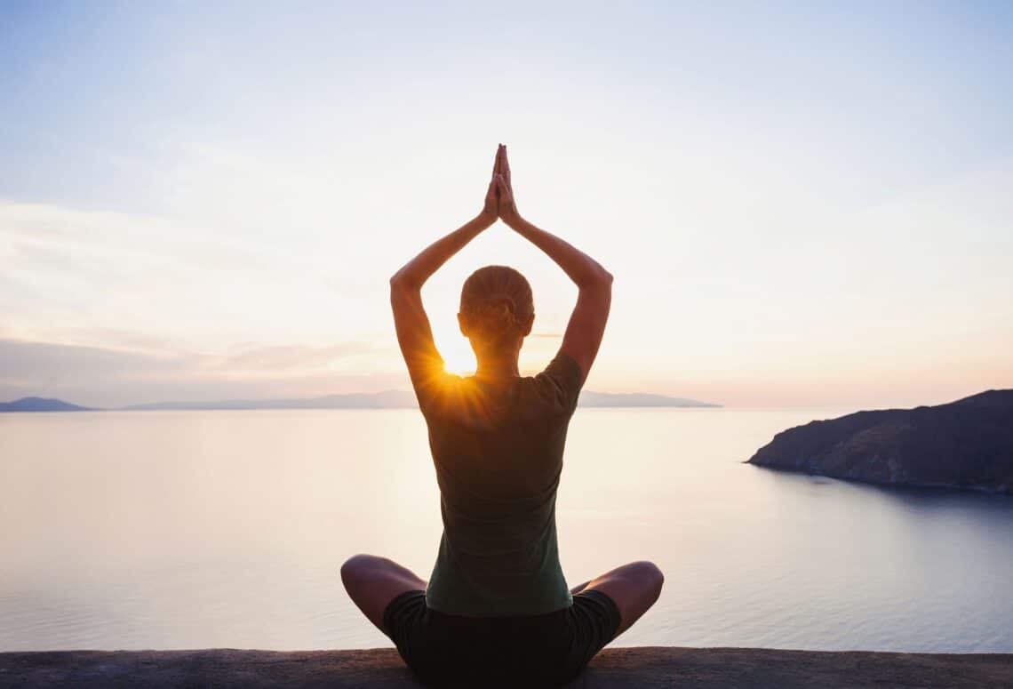 Frau macht Yoga am Rand einer Klippe