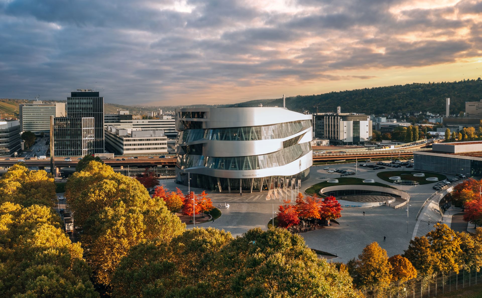 Moderne Architektur des Mercedes-Benz-Museums in Stuttgart umgeben von Herbstbaeumen und Innenstadt