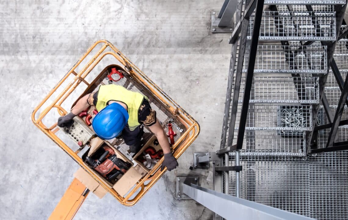 Bauarbeiter mit Schutzhelm arbeitet aus einem Arbeitskorb einer LKW-Arbeitsbühne