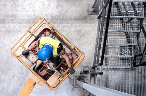 Bauarbeiter mit Schutzhelm arbeitet aus einem Arbeitskorb einer LKW-Arbeitsbühne