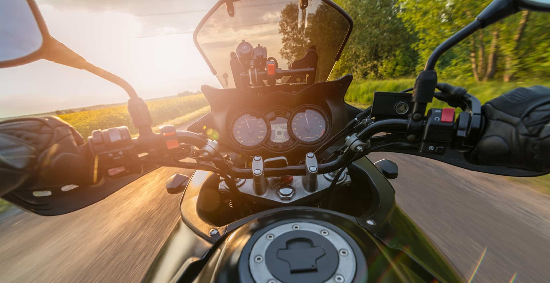 Motorradlenker mit Blick auf Landstraße bei Sonnenuntergang | Topcase