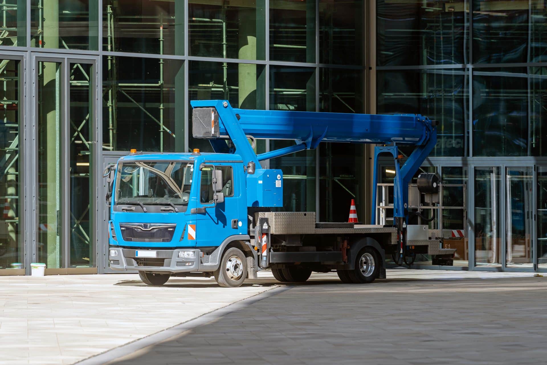 Blaue LKW-Arbeitsbühne steht vor einem modernen Bürogebäude